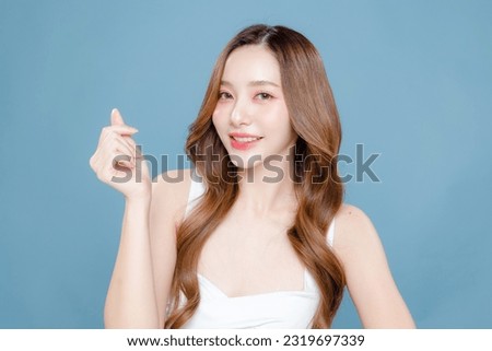 Young Asian beauty woman curly long hair with korean makeup style on face and perfect clean skin hold something in hand on isolated blue background. Facial treatment, Cosmetology, plastic surgery.