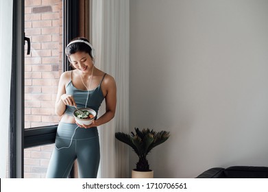 Young Asian Beauty Woman Eating Salad At Home Listening To Music