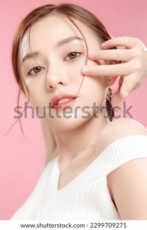 Young Asian beauty woman pulled back hair with korean makeup style touch her face and perfect skin on isolated pink background. Facial treatment, Cosmetology, plastic surgery.
