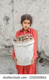 A Young Asian Boy Is Carrying A Heavy Basket Full Of Goods 