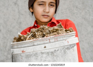 A Young Asian Boy Is Carrying A Heavy Basket Full Of Goods 