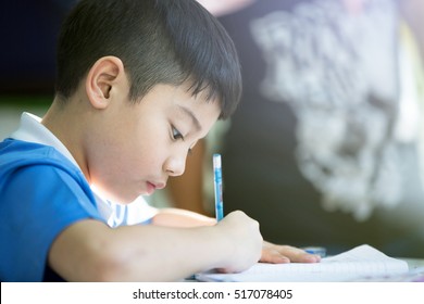 Young asian boy doing his homework , with sun light .