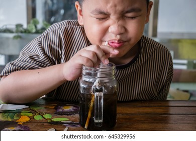 Young asian boy drinking cola soft drink. making sour/funny face.