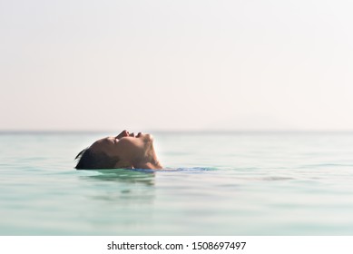 Young Asian Boy Floating On A Water Relaxing In Swimming Pool. 