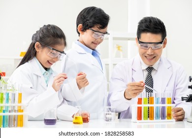 Young Asian Boy And Girl Smile And Having Fun While Learning Science Experiment In Laboratory With Teacher In Classroom. Study With Scientific Equipment And Tubes. Education Concept.