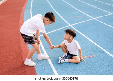 Young Asian Boy Give Hand To Help Accident Boy During Running On The Blue Track.