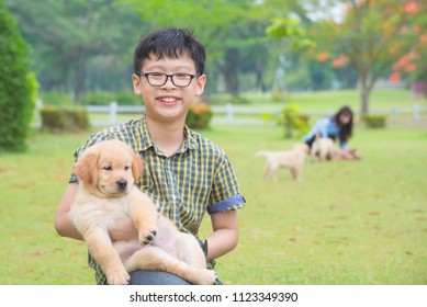 Young Asian Boy Holding His Dog And Smiles In Park