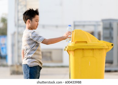 Young Asian Boy Plastic Bottle For Eliminate In The Yellow Bin Under The Sunlight