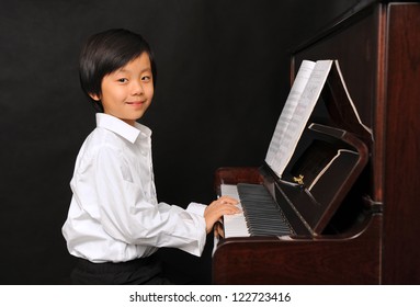 Young Asian Boy Playing Piano  (isolated On Black Background)