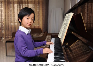 Young Asian Boy Playing Piano At Home