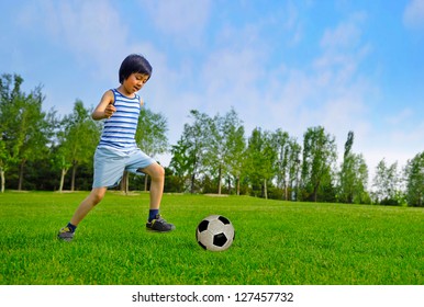 Young Asian Boy Playing Soccer Outdoors