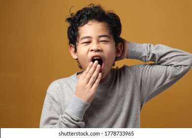 Young Asian boy sleepy and yawning, tired exhausted gesture not enough to rest at night, against yellow background - Powered by Shutterstock