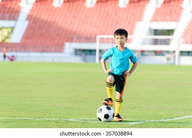 Young Asian Boy Stand In The Grass Football Field In The Stadium During Summer.