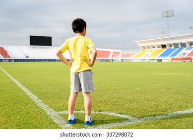 Young Asian Boy Standing On Green Football Field In Stadium During Day Time And Feel Relax.