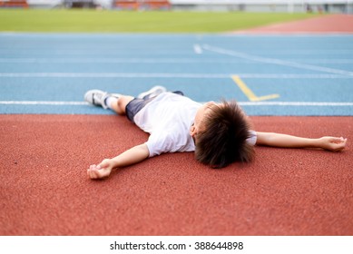 Young Asian Boy Tired And Lay Down On The Running Track.