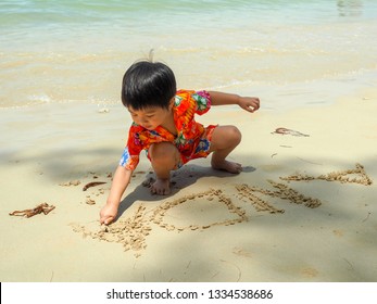 Young asian boy writing his name ANDA on the sands, playing on the beach during summer time.  - Powered by Shutterstock