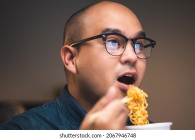 Young Asian Business Freelancer Working At Late Night. He Very Hungry And Eating Hot Instant Noodle And Work With Computer In The Dark Office At Night.