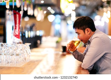 Young asian business man or freelancer sitting at night club bar drinking beer feeling thoughtful. Alcohol de-stressing for self medicating to relieve depressed after work concept with copy space. - Powered by Shutterstock