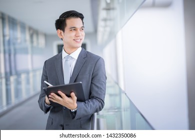 Young Asian Business Man Holding A Tablet Looking Away