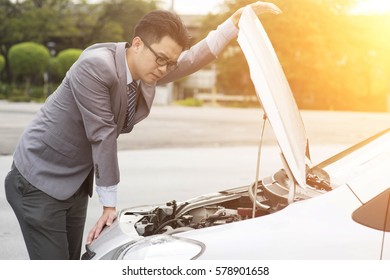 Young Asian Business Man Looking Under The Hood Of Breakdown Car.