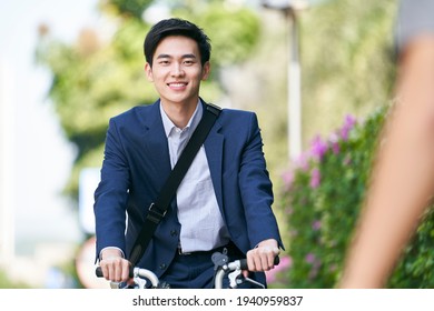 young asian business man riding bicycle to or from work, happy and smiling
