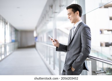 Young Asian business man smile holding smart phone at office area,man smart business concept.