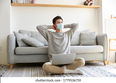 young asian business man staying at home wearing mask sitting on carpet working using laptop computer - Powered by Shutterstock