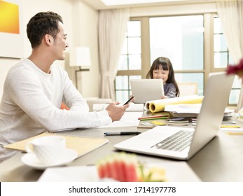 young asian business man taking care of child while working from home (artwork in background digitally altered) - Powered by Shutterstock