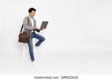 Young Asian Business Man Using Laptop Computer And Sitting On White Chair Isolated On White Background, Full Length Composition