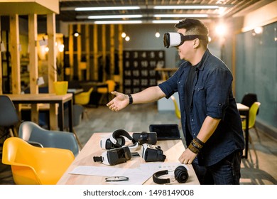 Young Asian business man wearing virtual reality goggles using hand for shaking - Powered by Shutterstock