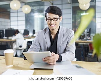 Young Asian Business Man Working In Office Using Tablet Computer.