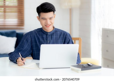 Young Asian Business Man Writing On Notebook For Planning Working And Using Laptop Computer On Desk At Home, Notes About Finance, Male Study And Learning, Business And Communication Concept.