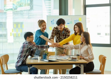 Young Asian Business People Putting Their Hands Together. Stack Of Hands And Together Working On New Startup Project. Unity And Teamwork Concept.