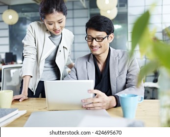young asian business people sitting at desk working together using laptop computer.