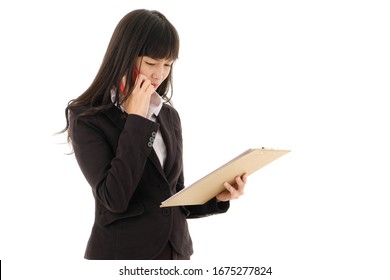 Young Asian  Business Woman In Black Suit With Long Hair Holding Document On Clipboard And Talking On The Mobile Phone On White Background,Serious Business Woman Looking At Documents,studio Isolated.