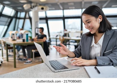 Young Asian business woman employee or executive manager using computer looking at laptop and talking leading hybrid conference remote video call virtual meeting or online training working in office.