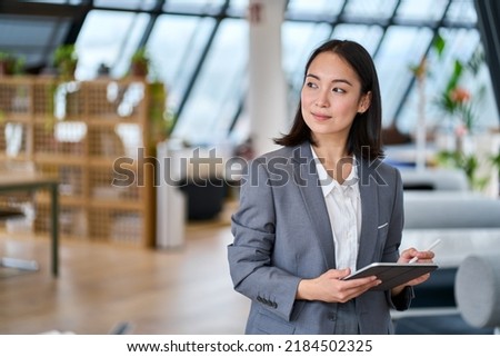 Young Asian business woman entrepreneur standing in office holding digital tablet. Businesswoman leader, professional company manager using smart corporate management technology looking at copy