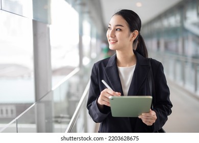Young Asian business woman holding a tablet looking away, Fashion business photo of beautiful girl in casual suite with tablet . - Shutterstock ID 2203628675