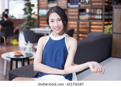 Young Asian business woman sitting down on sofa with luxury dress and white skirt looking to the camera with smart and intelligent emotion