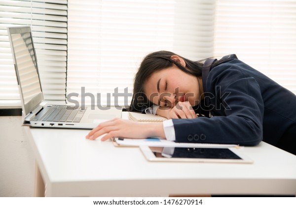 Young Asian business woman Sleep on table in office\
because overworking , stressed from work overload and is a tired\
and sleepy lady.  