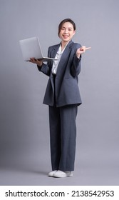 Young Asian Business Woman Standing On Gray Background