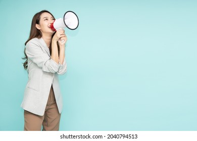 Young Asian Business Woman In Suit Holding Megaphone Isolated On Green Background, Speech And Announce Concept