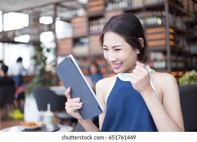 Young Asian business woman surprising while looking to tablet after checking her profit income or stock trading