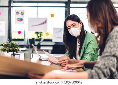 Young Asian Business Woman Using Laptop Computer Working And Planning Meeting In Quarantine For Coronavirus Wearing Protective Mask With Social Distancing While Sitting On Office Desk