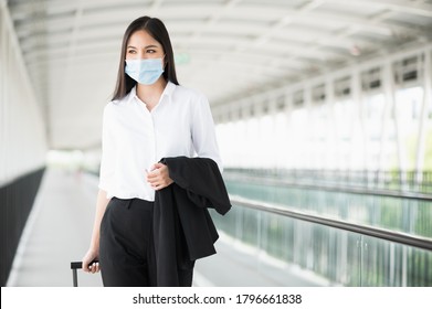 Young asian business woman wearing protection mask walking in airport terminal with trolley bag.