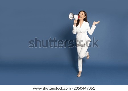 Young Asian business woman in white suit holding megaphone isolated on blue background, Speech and announce concept, Full body composition
