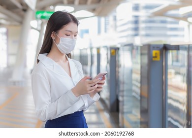 Young Asian business woman who has long hair wears medical face mask protect health from Coronavirus (COVID-19) to prevent disease virus while using the smartphone in her hand to contact the office. - Powered by Shutterstock