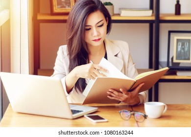 young Asian business woman working at workplace. beautiful Asian woman in casual suit working with reading book, prepare for meeting or interview in modern office. freelance, start up business in Asia