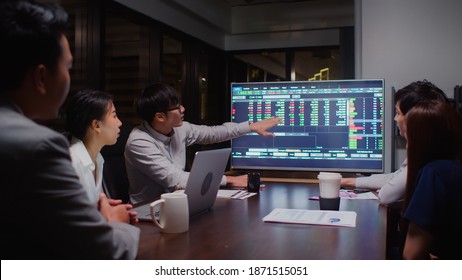 Young Asian businessman lead group of business financial team in strategic meeting presentation, work late night in office. Marketing strategy analysis, stock market trading, or corporate teamwork - Powered by Shutterstock