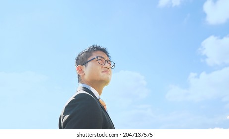 Young Asian Businessman Looking Up At The Sky.